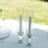 Two elegant glass candle holders with white candles inside.