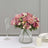Floral arrangement with pink roses and mixed flowers in a clear glass vase.