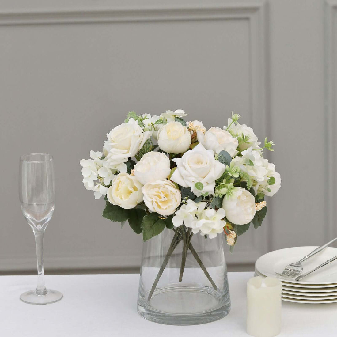 Elegant white floral arrangement in a glass vase with greenery.