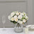 Elegant white floral arrangement in a glass vase with greenery.