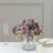 Purple floral arrangement in a glass vase with elegant table setting.