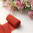 Rust-colored fabric roll on a light background with floral arrangement.
