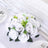 White artificial rose bouquet with green accents on a table setting.