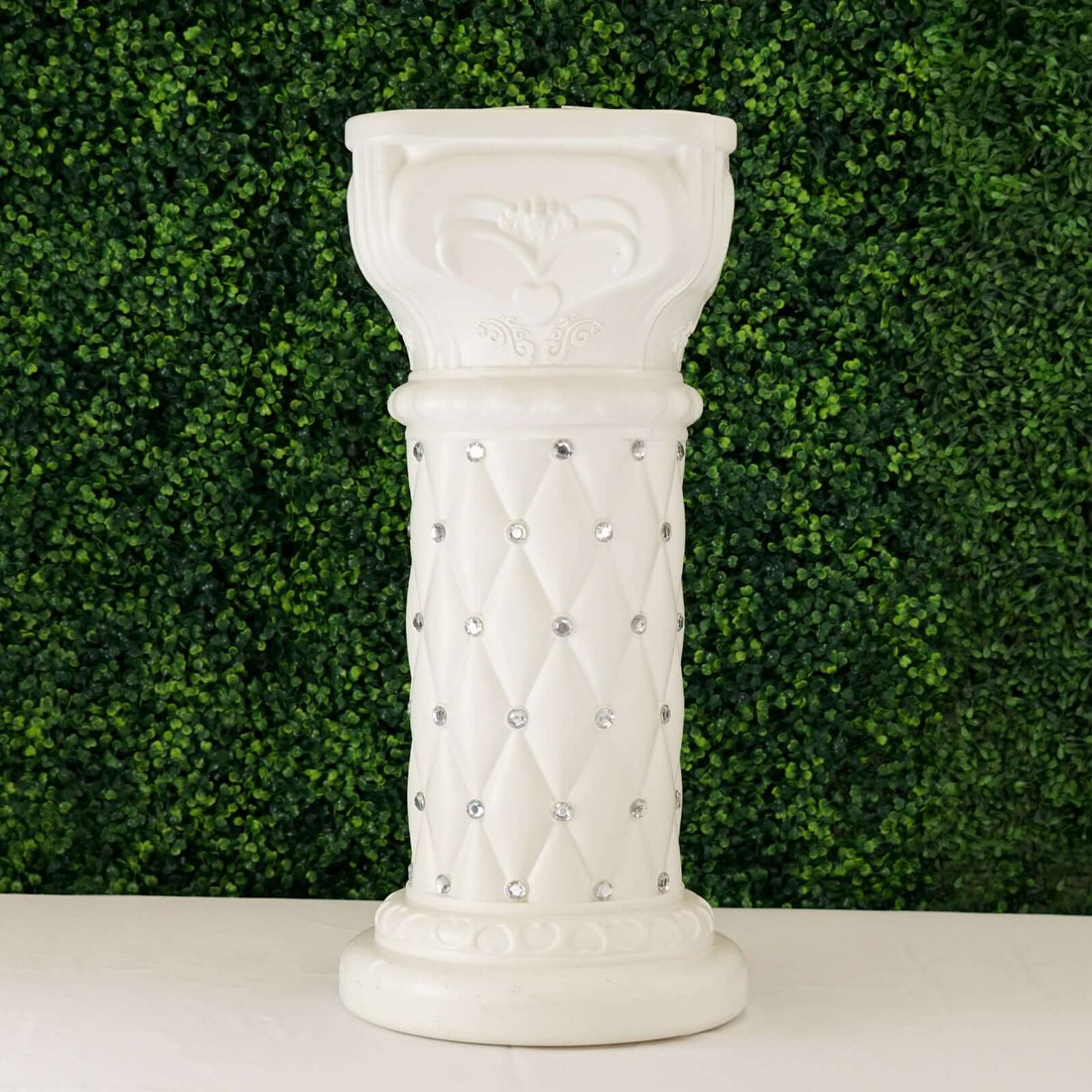 White decorative column with diamond embellishments on a green background.