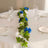 Elegant table setting with blue and white rose garland and glassware.