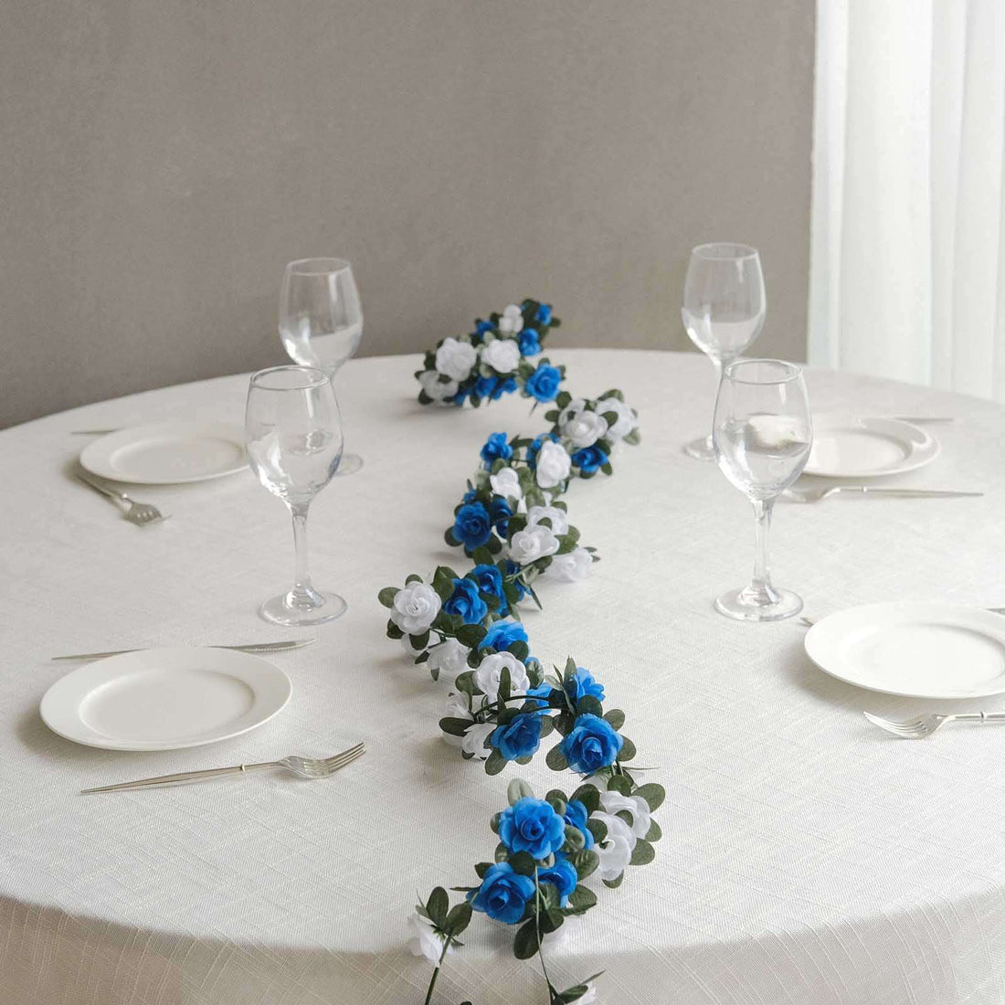 Blue and white floral table centerpiece on a round table with glassware.