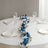 Blue and white floral table centerpiece on a round table with glassware.