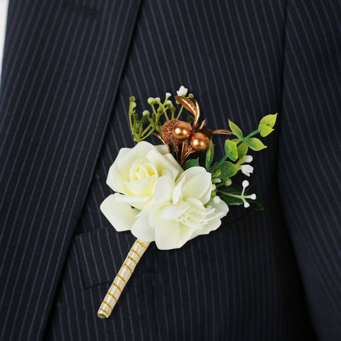 White floral boutonniere with greenery on a dark suit jacket.