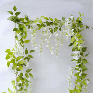 Artificial flower garland with green leaves and white blooms on a plain background