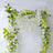 Artificial flower garland with green leaves and white blooms on a plain background