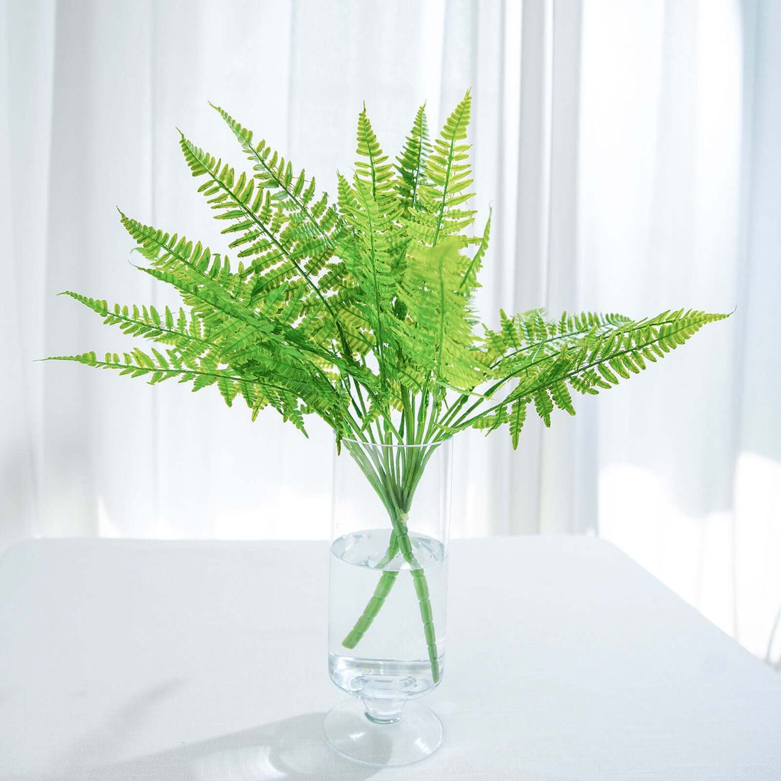 Green fern arrangement in clear vase, fresh look for home decor.