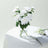 White flower bouquet in a glass vase on a table with a magazine.