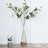 Artificial white rose bouquet in a clear vase with decorative stones.