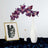 Orchid arrangement in a white vase with decorative art and accessories.