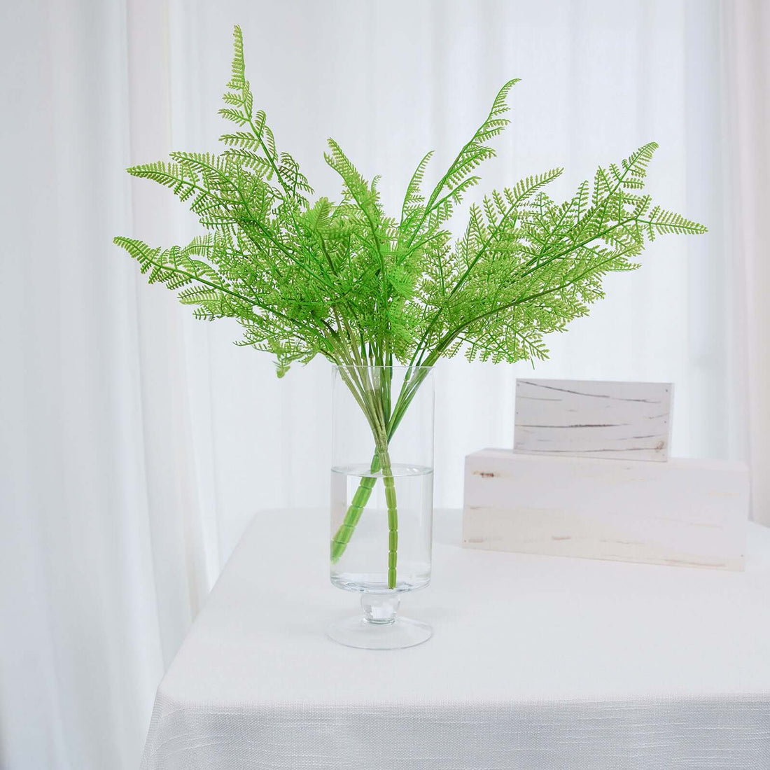 Green fern arrangement in a clear vase on a table