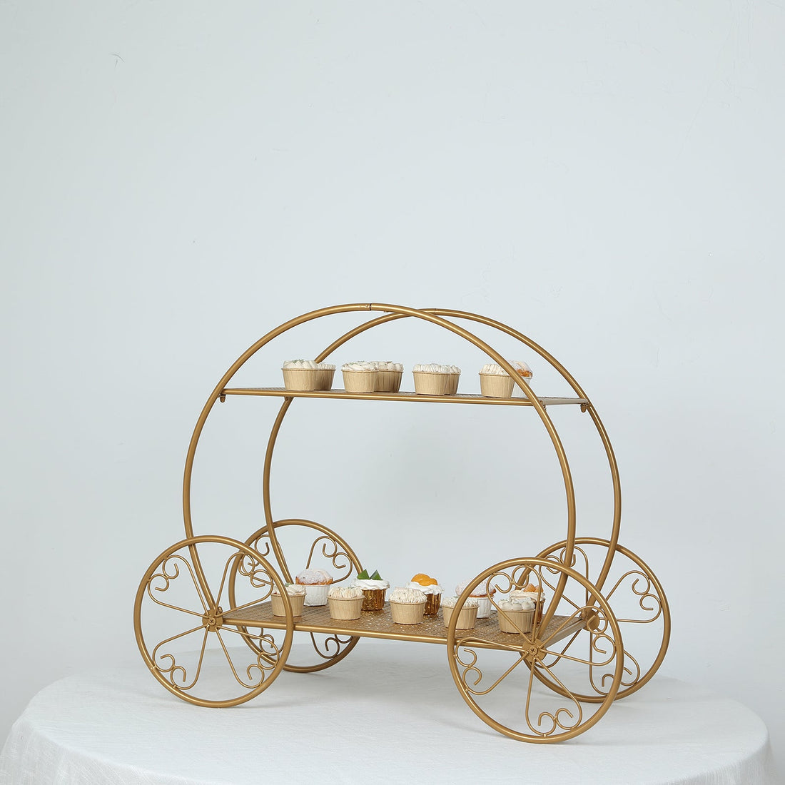 Gold cupcake cart with two tiers and decorative wheels, displaying various cupcakes.