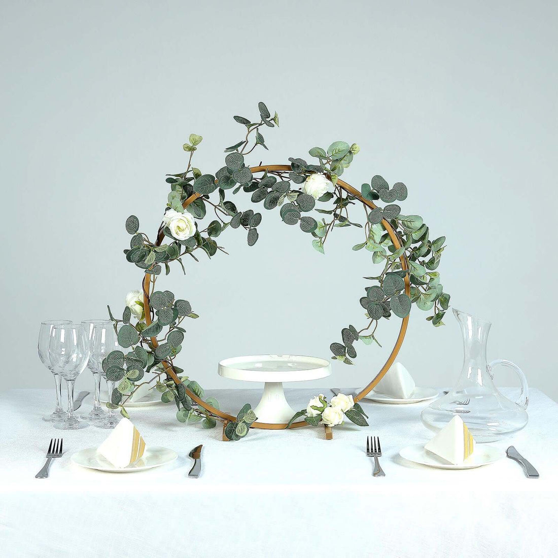 Decorative floral hoop centerpiece on a dining table with elegant tableware.