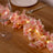 Pink floral garland with lights on a wooden table setting.