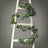 Eucalyptus garland draped on a wooden ladder for decorative display.