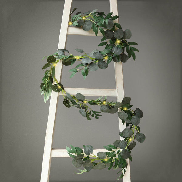 Eucalyptus garland draped on a wooden ladder for decorative display.