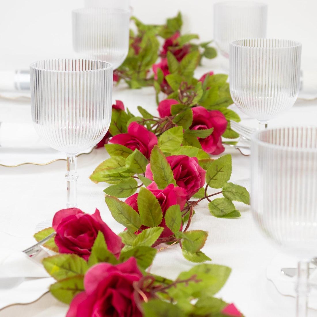Elegant table setting with clear glassware and pink floral decor.