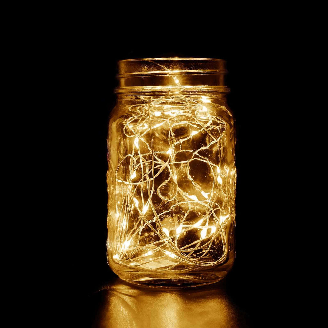 Mason jar filled with warm white fairy lights glowing in the dark. #whtbkgd