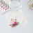 Floral decorative napkin with geometric gold accents and a glass on top.
