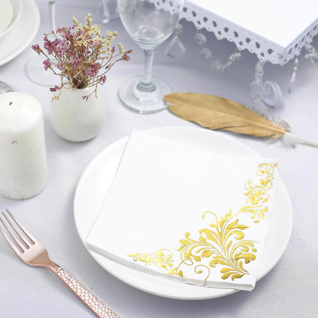 Elegant white napkin with gold floral design on a plate, styled for special occasions.