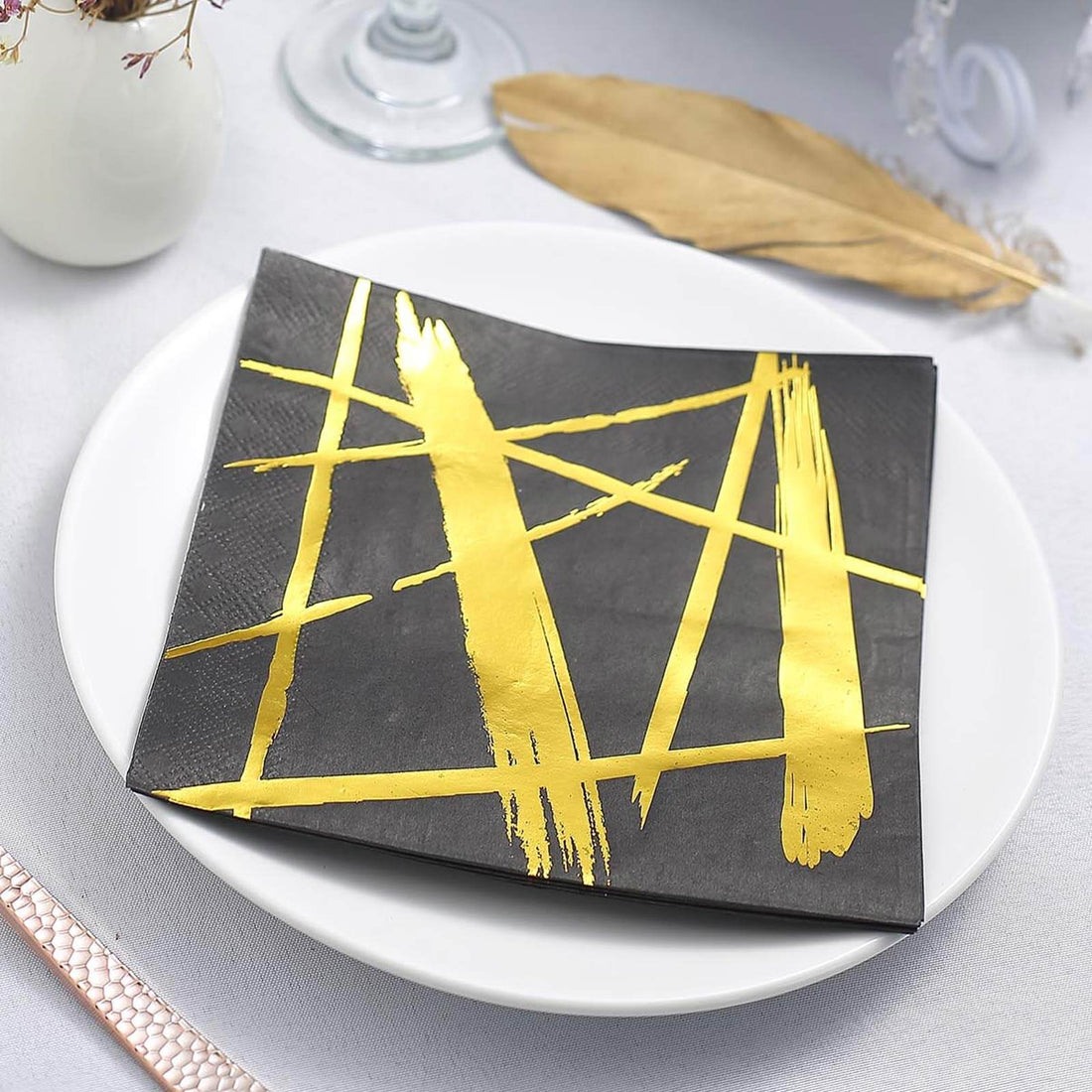 Black plate with gold brushstroke design on a white dish.