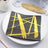 Black plate with gold brushstroke design on a white dish.