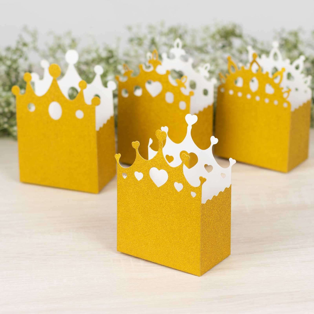 Gold crown party favor boxes with decorative cutouts.