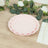 Pink scalloped plates stacked on a wooden table with greenery and flowers.