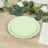 Green scalloped plates stacked on a wooden table with greenery and flowers.
