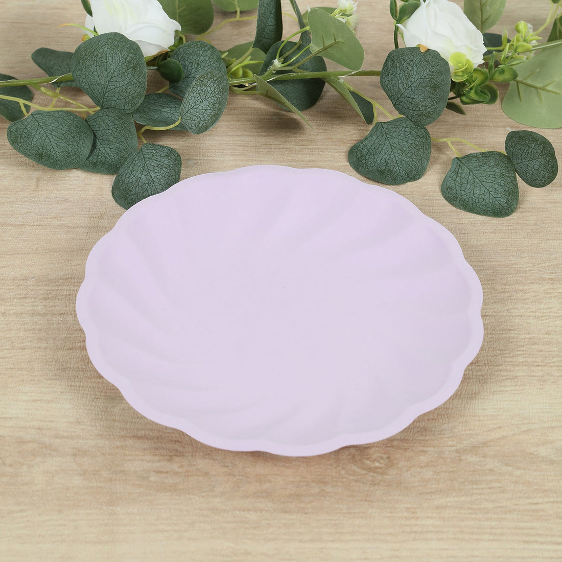 Purple scalloped plate on a wooden surface with greenery.