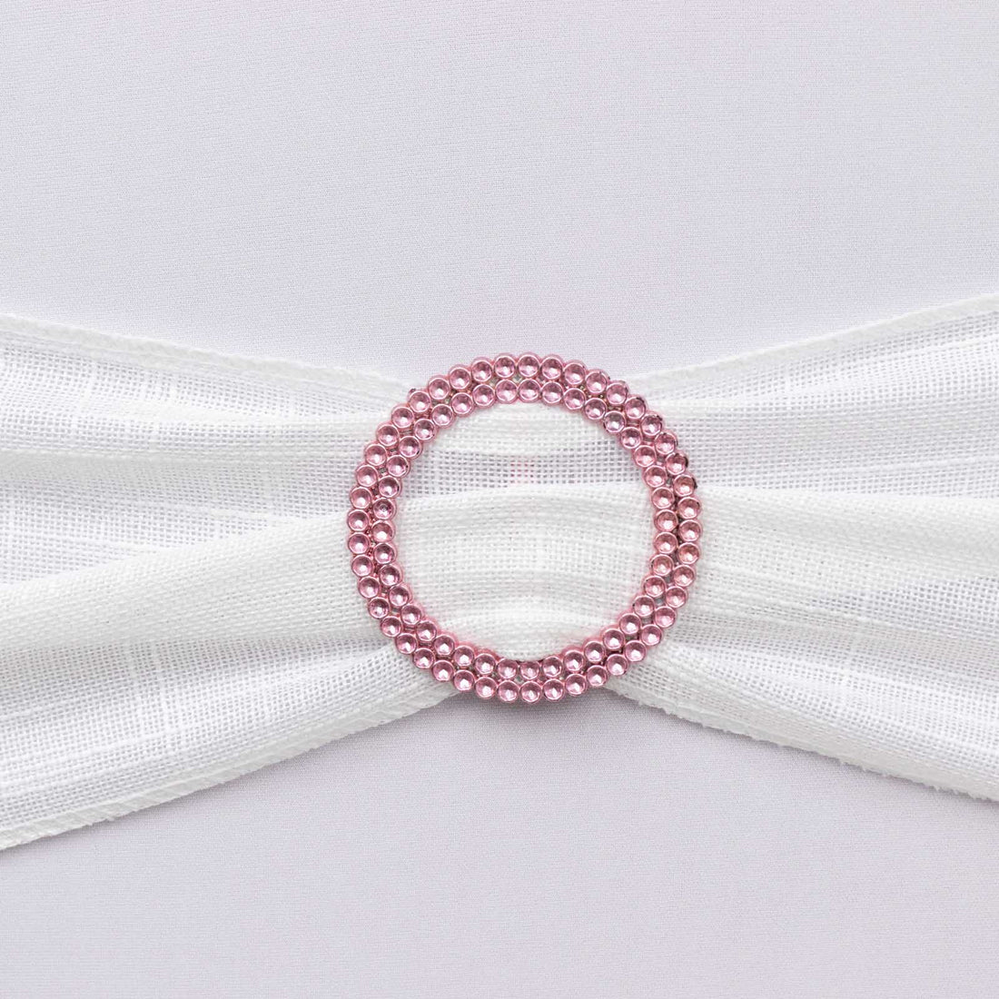 Pink rhinestone circular brooch on white fabric ribbon