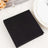 Black napkin set on a table with a plate and wine glass.