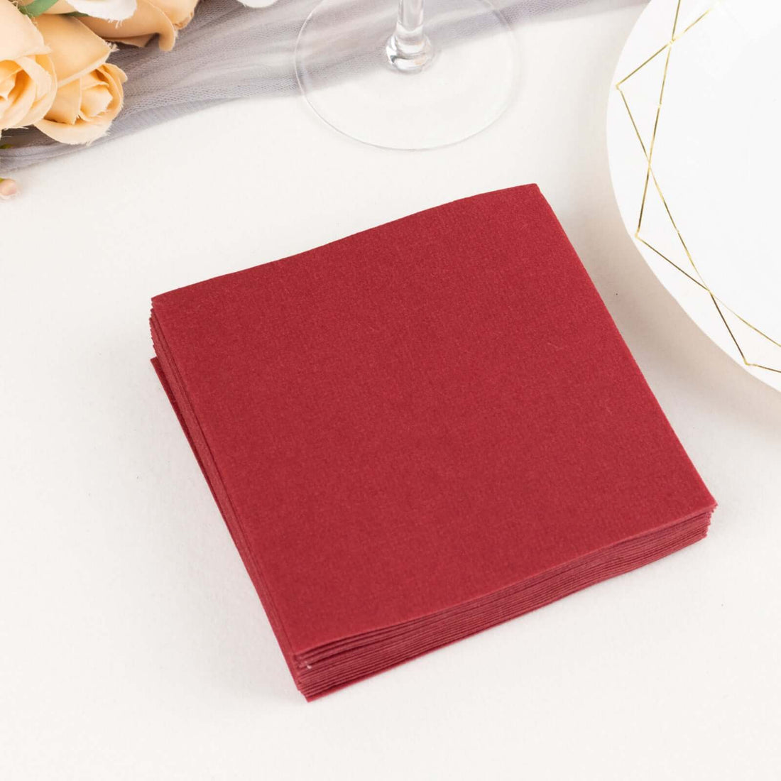 Stack of burgundy paper napkins on a table setting.