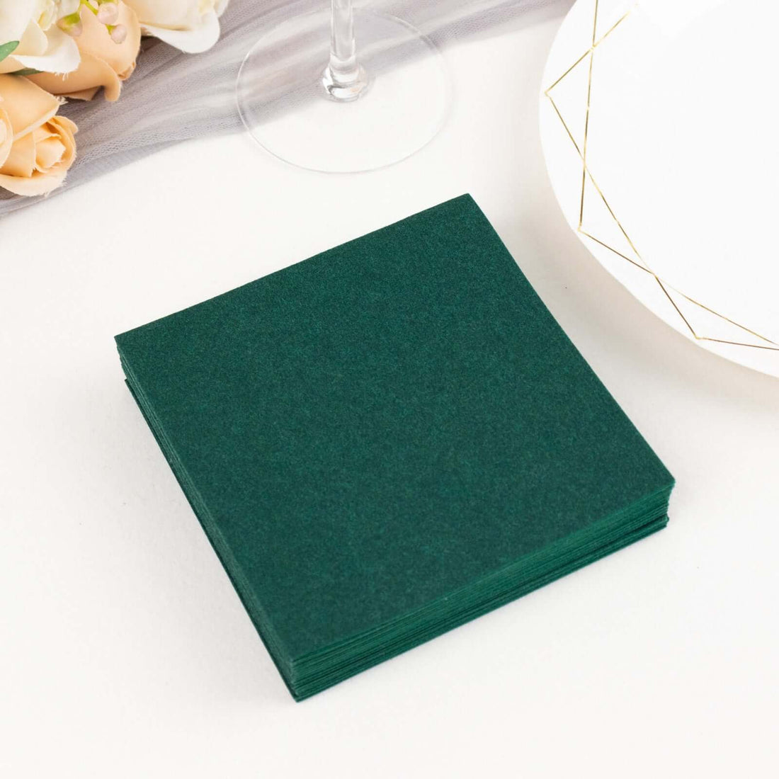 Green paper coasters stacked on a table with a plate and decorative elements.