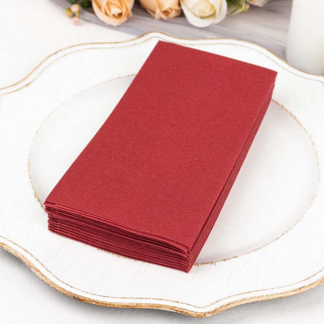 Stack of burgundy napkins on a decorative plate.
