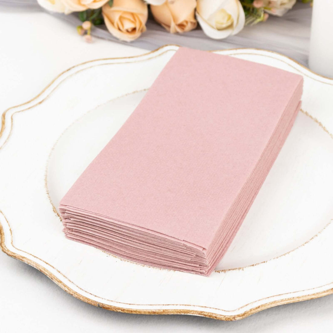 Stack of pink paper napkins on a decorative plate.