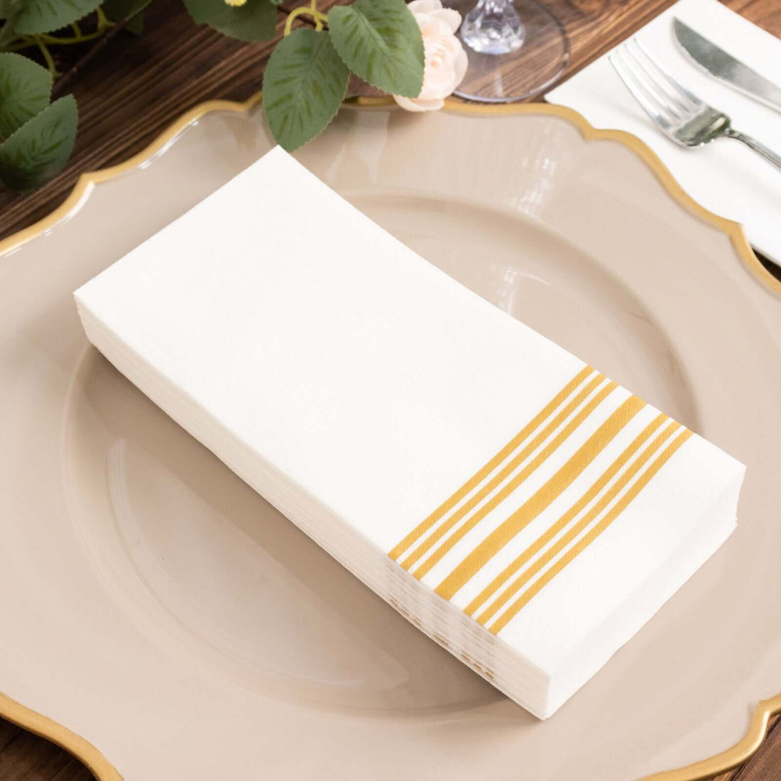 White napkins with yellow stripes on a decorative plate.