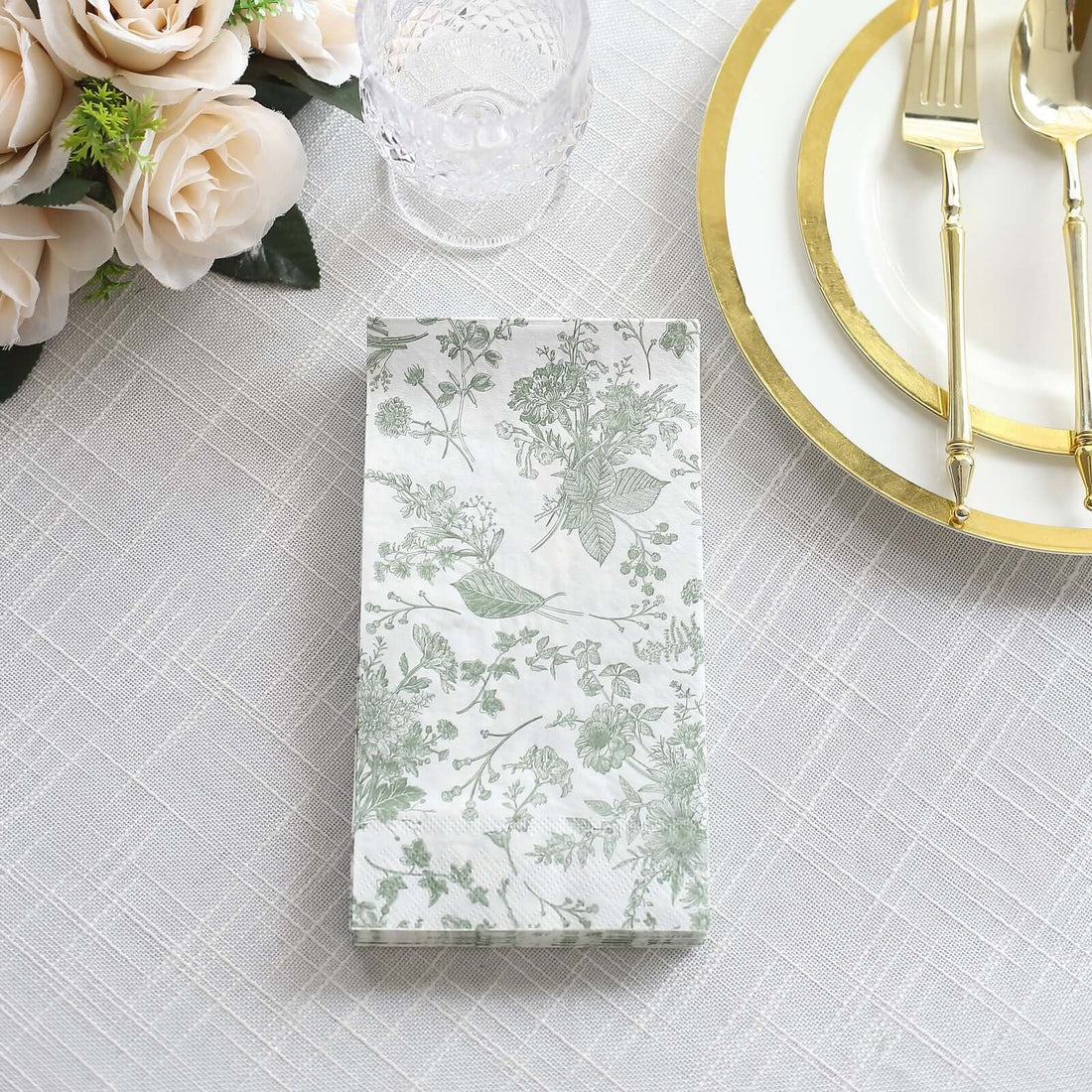 Floral patterned napkin on a table setting with gold utensils and glassware.