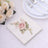 Floral design paper napkin on a table setting with silver cutlery and roses.