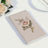 Embroidered rose design on a beige notebook against a white background