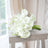White calla lily bouquet arranged on a wooden stool.