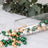 Colorful decorative beads in green, gold, and silver spilling from a glass vase.