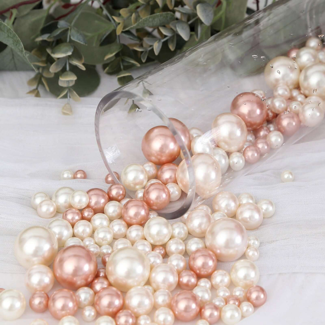 Assorted pearl beads spilling from a clear vase