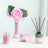 Decorative pink flower vase, candle holder, and ribbon on a table.