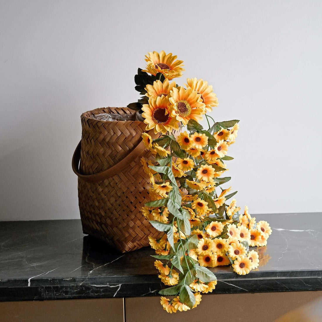 Woven basket with sunflowers cascading over a marble countertop.