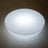 Round glowing white light fixture on a plain background